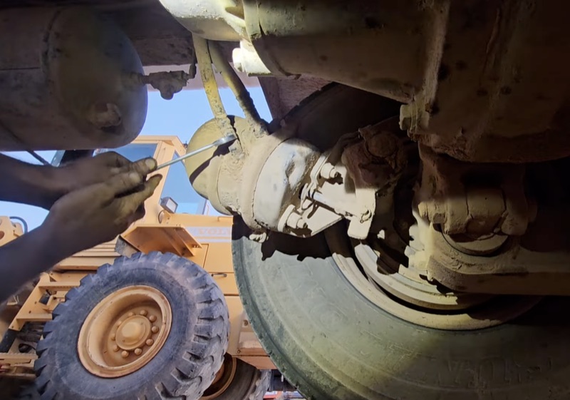Technician working on brake components underneath a commercial vehicle